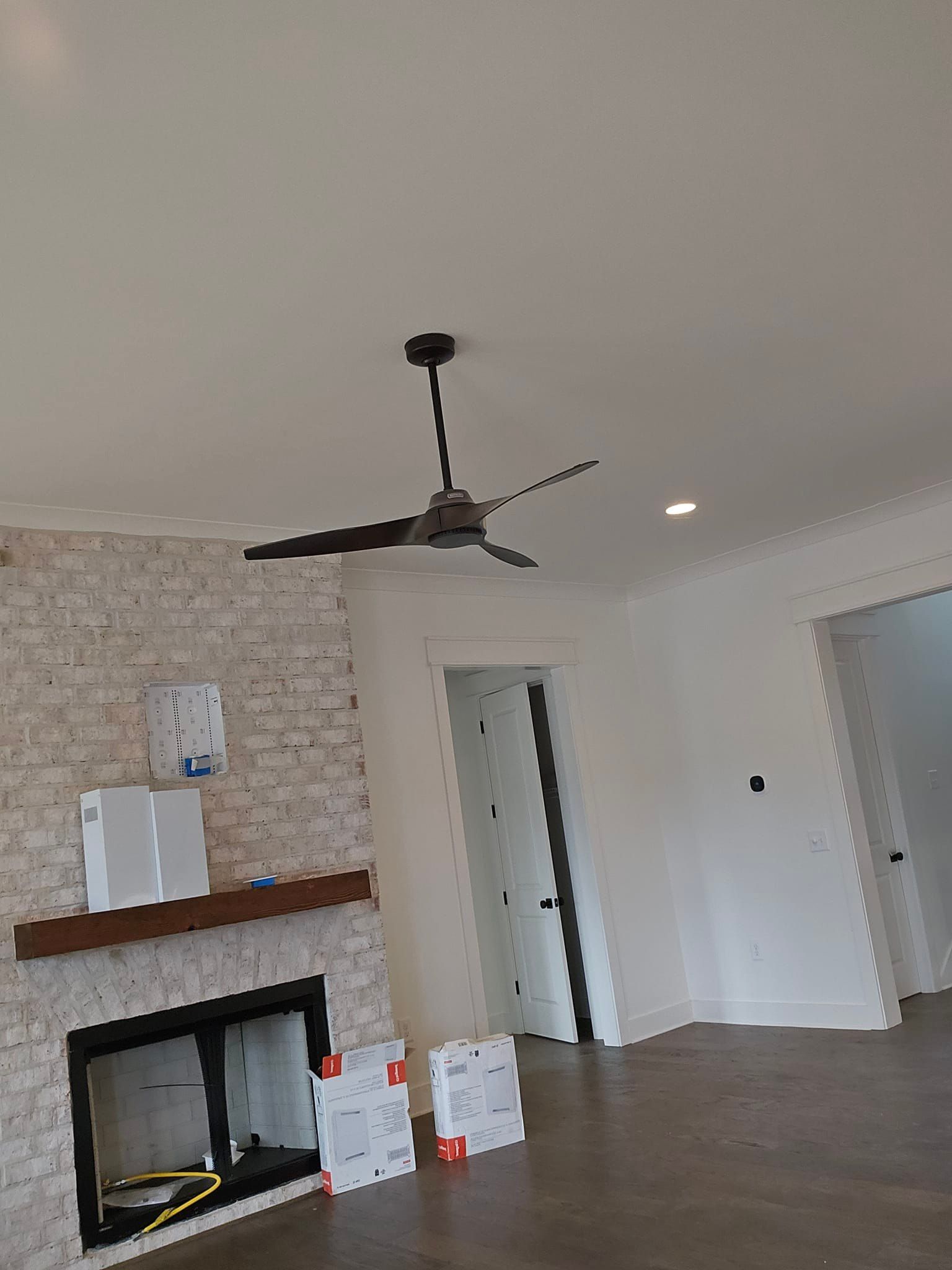 Room interior with fireplace, fan, doors, and white walls.