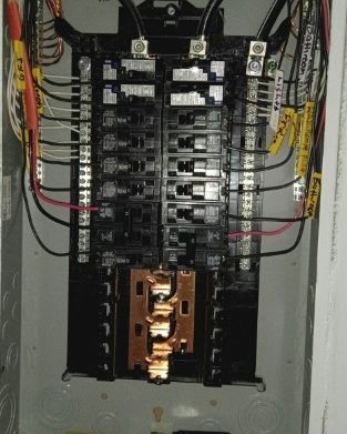 Electrical panel with circuit breakers and wiring.