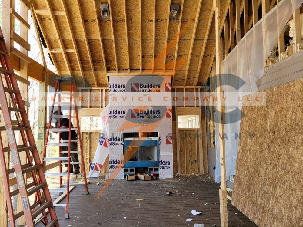 Interior of a house under construction. Wooden framing, fireplace, and ladder visible.