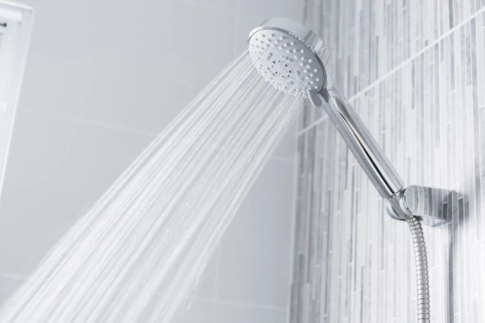 A Shower Head Is Spraying Water In A Bathroom — Cairns Clear Water Company In Westcourt, QLD