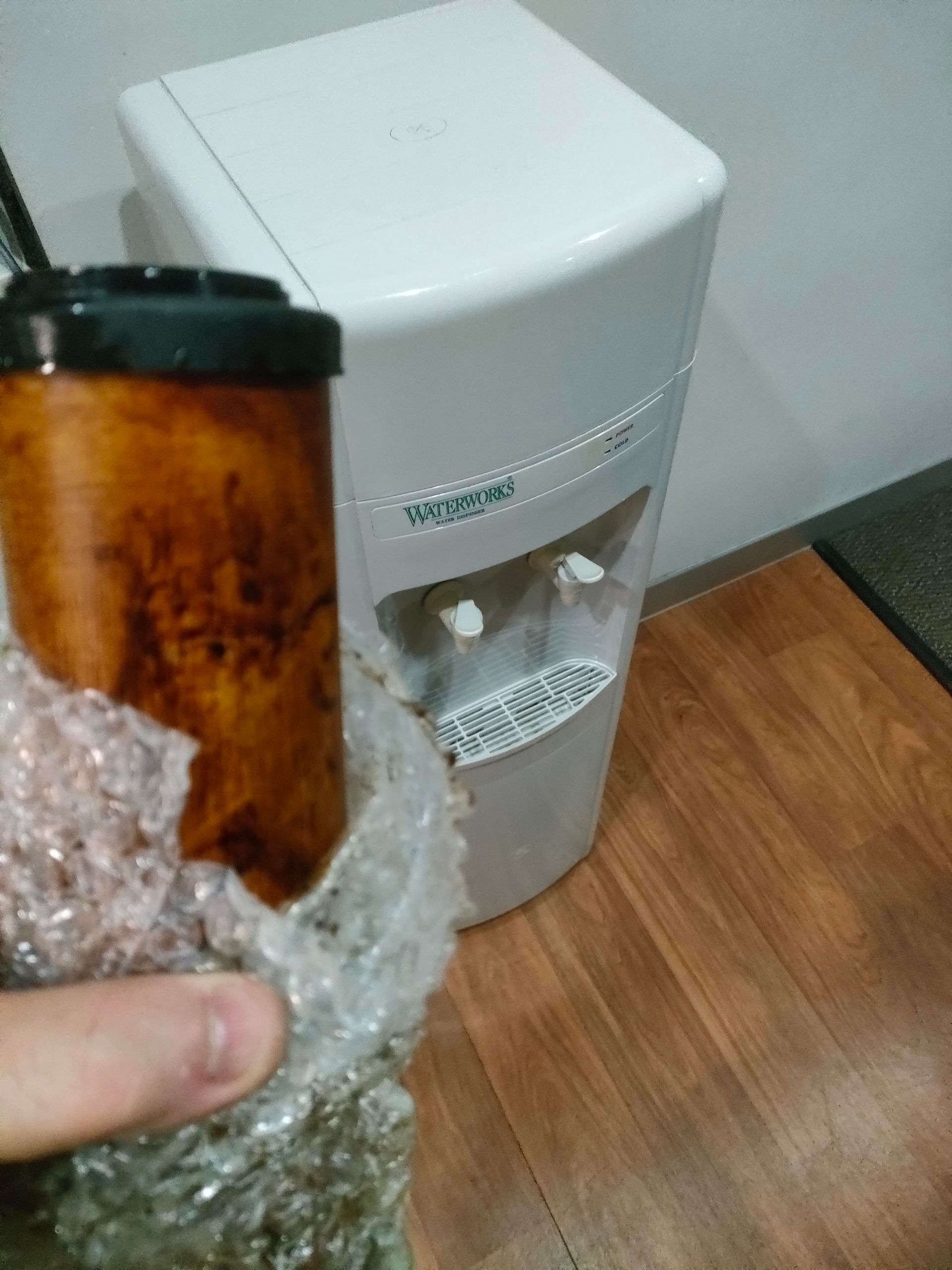 A Person Is Holding A Wrench In Front Of A Water Filter — Cairns Clear Water Company In Cassowary Coast, QLD