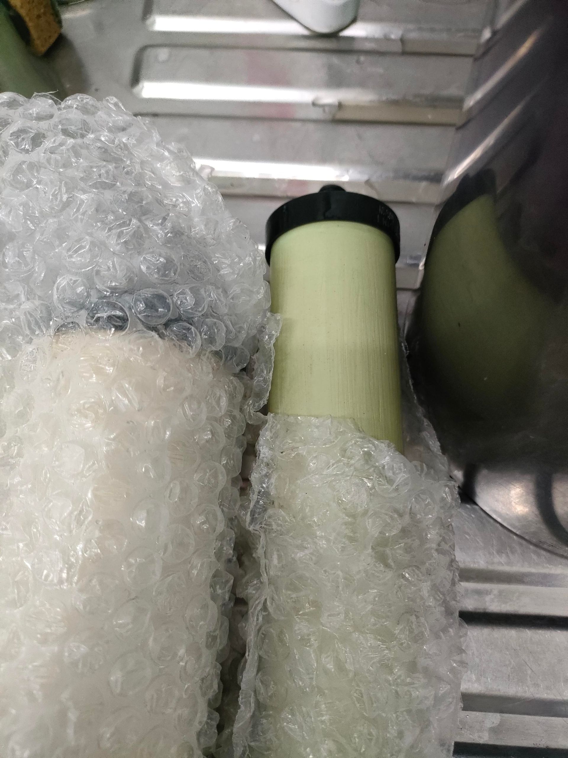 A Man Is Fixing A Water Filter In A Kitchen — Cairns Clear Water Company In Westcourt, QLD
