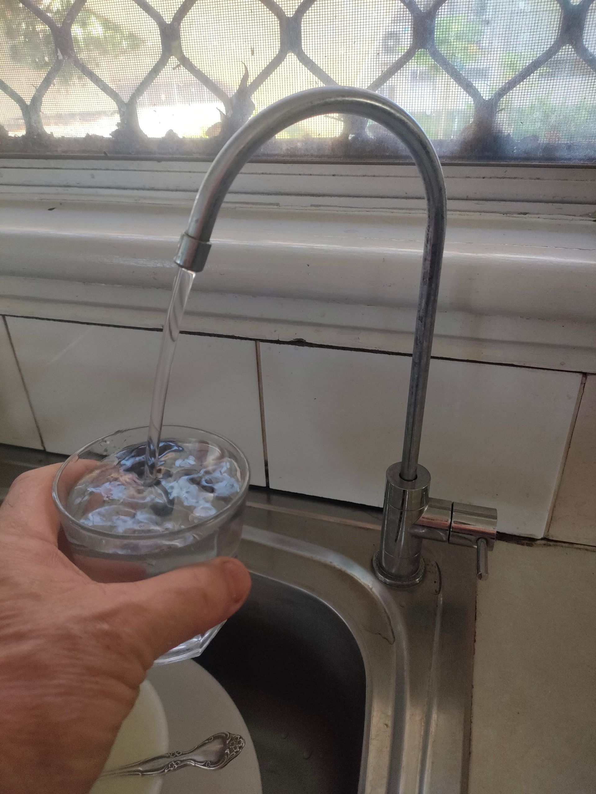 A Person Is Installing A Water Filter In A Bathroom — Cairns Clear Water Company In Cassowary Coast, QLD