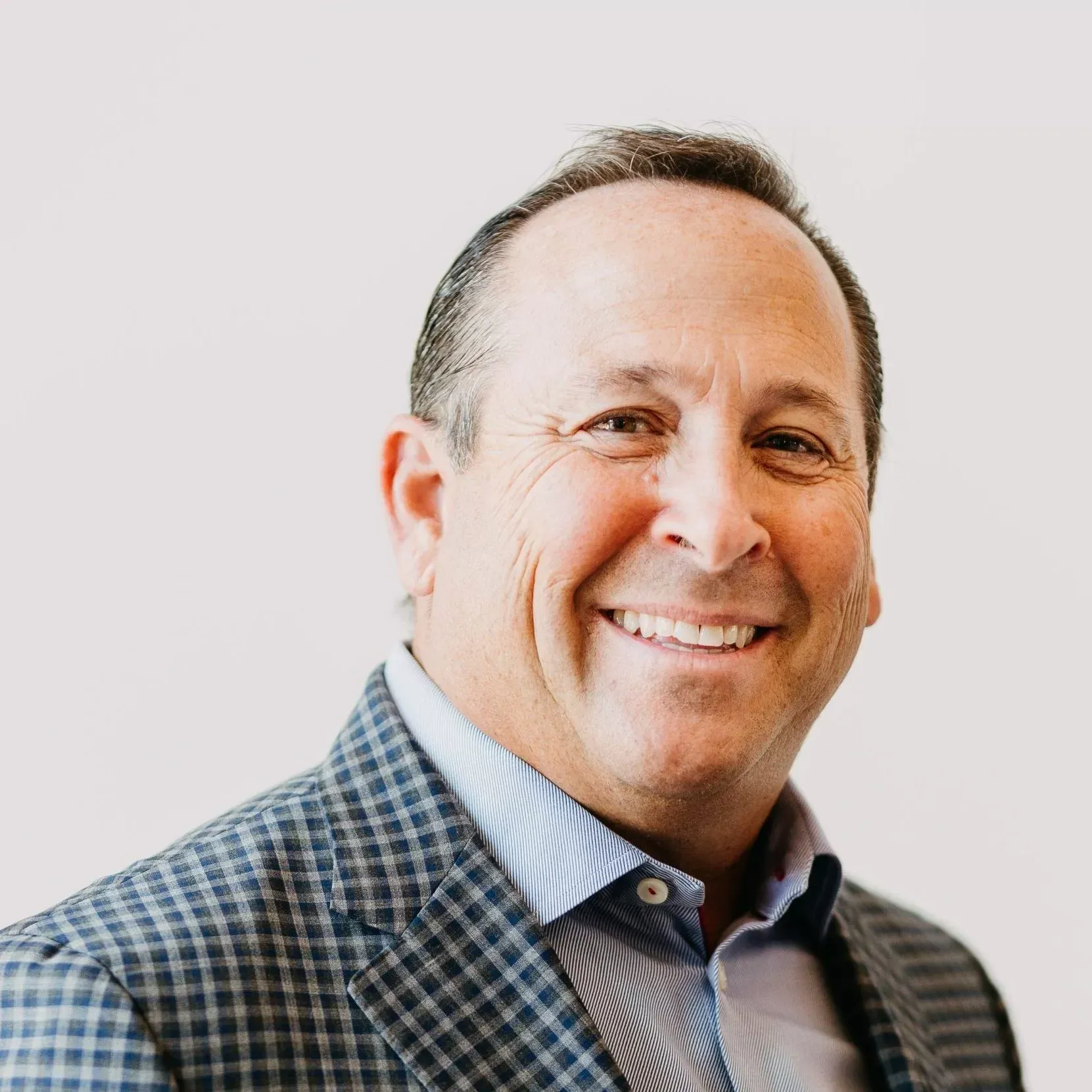 A man in a suit and striped shirt is smiling for the camera.