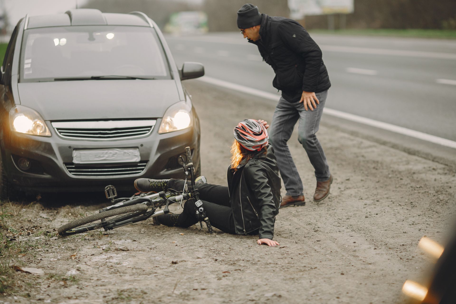A man is helping a woman who has fallen off her bike.