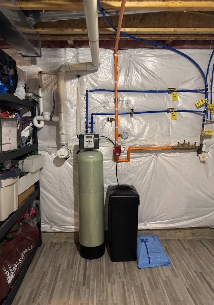 Water softener and salt tank in a basement, with associated pipes and shelving.