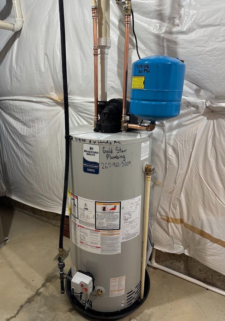 A water heater with copper pipes, a blue expansion tank, and a black exhaust pipe. Located in a basement.