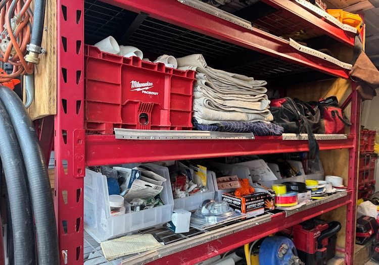 Red shelving unit holding various tools and supplies in a workshop.