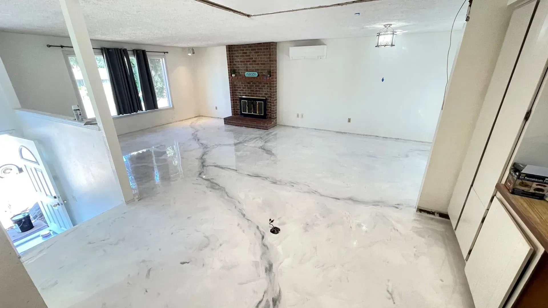 Elite Surface Coatings - Bright, spacious room with white, marbled floors. Brick fireplace and large windows.