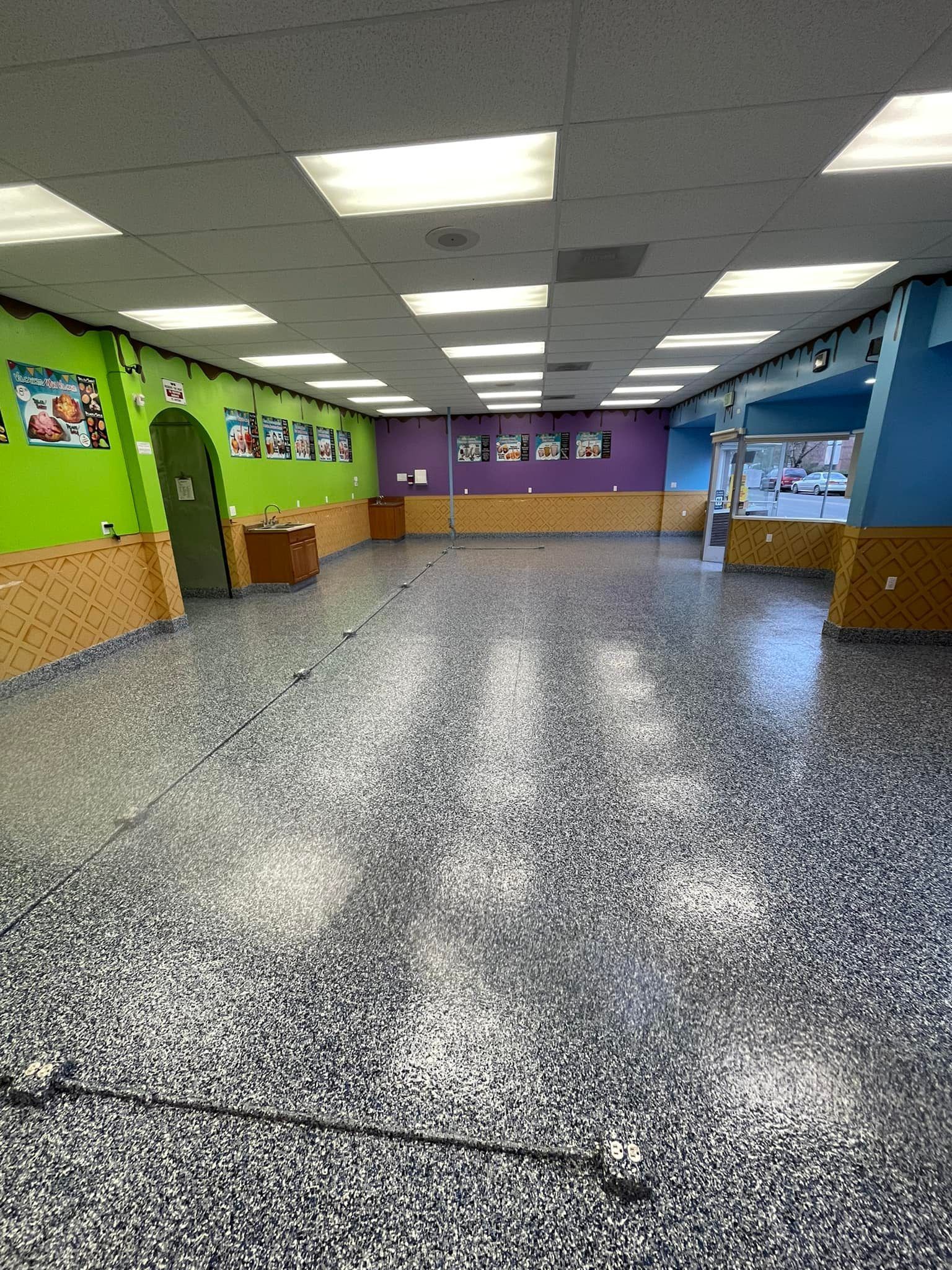 Elite Surface Coatings - Empty, brightly lit room with colorful walls: green, purple, and blue.