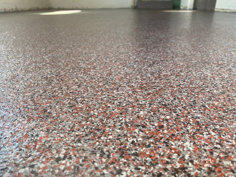 Elite Surface Coatings -View of a speckled epoxy floor with red, gray, black, and white chips.