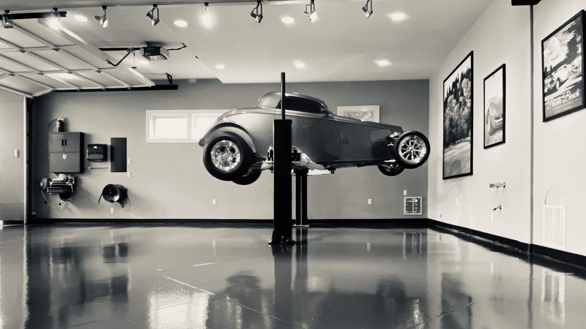 Elite Surface Coatings - Hot rod on a lift in a shiny garage with artwork on the walls.