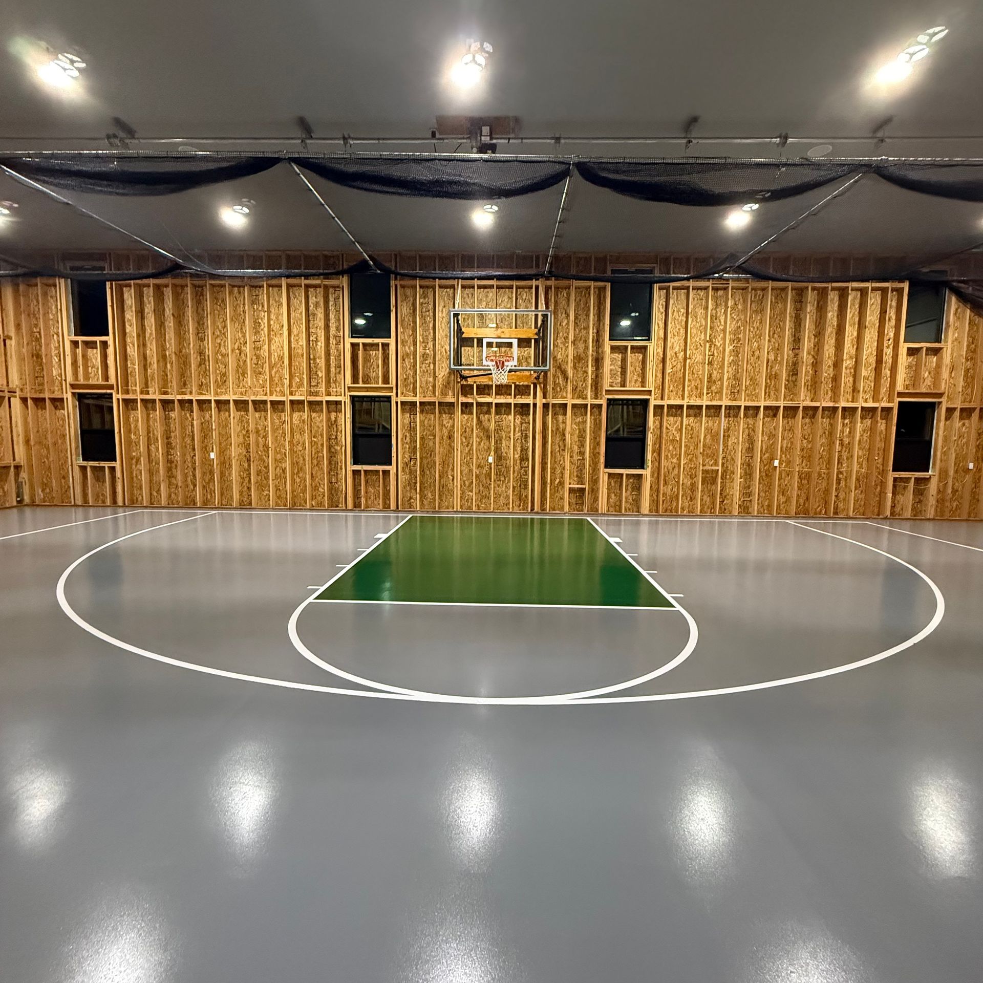Elite Surface Coatings - Indoor basketball court with gray floor and wooden walls.