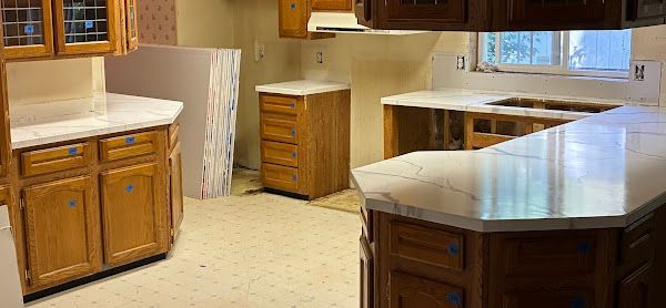 Elite Surface Coatings - Kitchen with wooden cabinets, countertops, and an island, undergoing renovation.