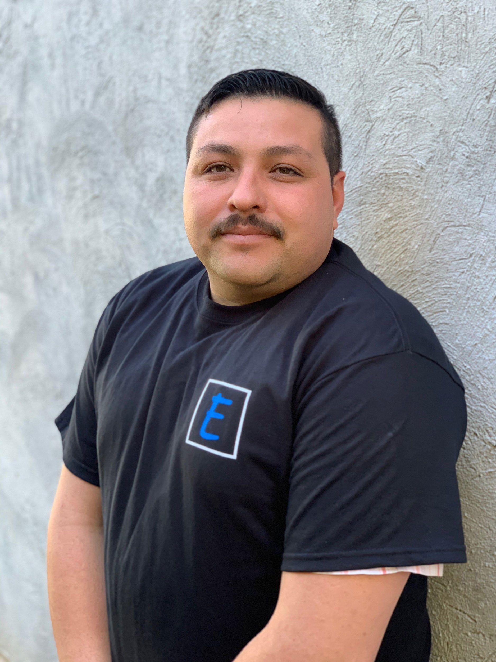 Elite Surface Coatings - A man in a blue hoodie is leaning against a wall and smiling.