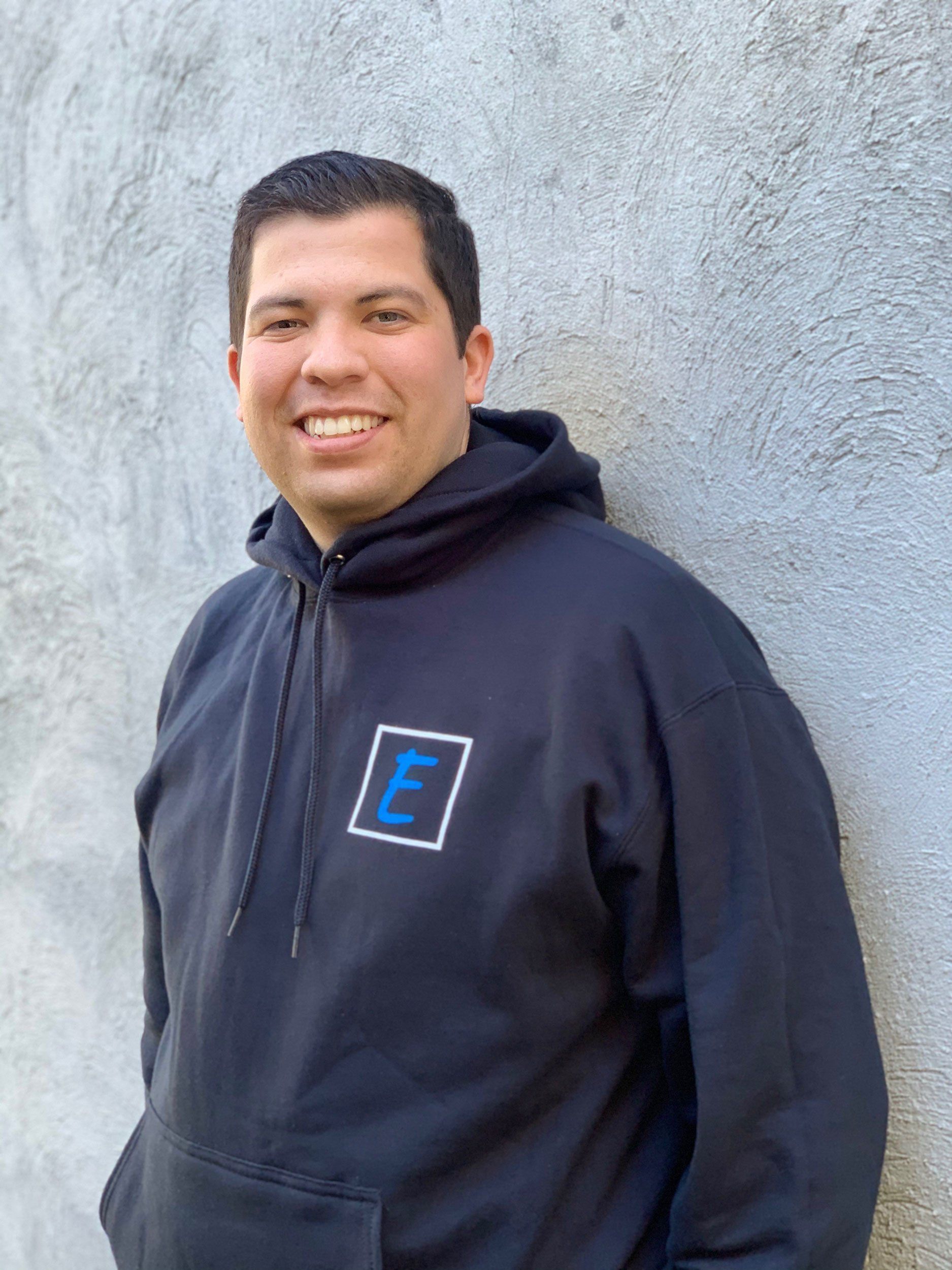 Elite Surface Coatings - A man in a blue hoodie is leaning against a wall and smiling.