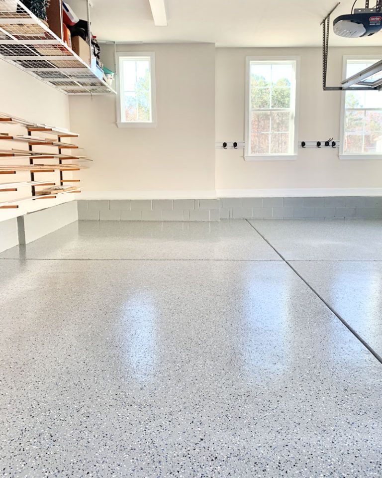 Elite Surface Coatings - Garage with light gray speckled epoxy floor, white walls, windows, and shelving.