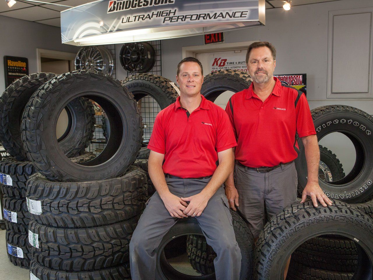 Two men posing in front of tire display at KB Tire & Auto