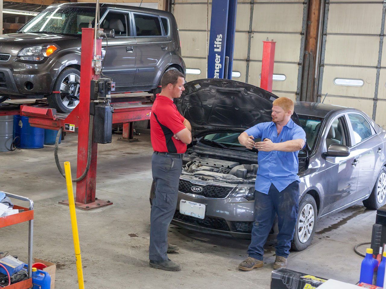 Two automotive technicians discussing repairs at KB Tire & Auto located in Moberly, MO