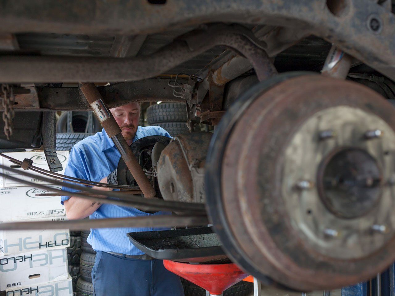 Close up of an automotive technician working on axels of a raised vehicle with wheels removed