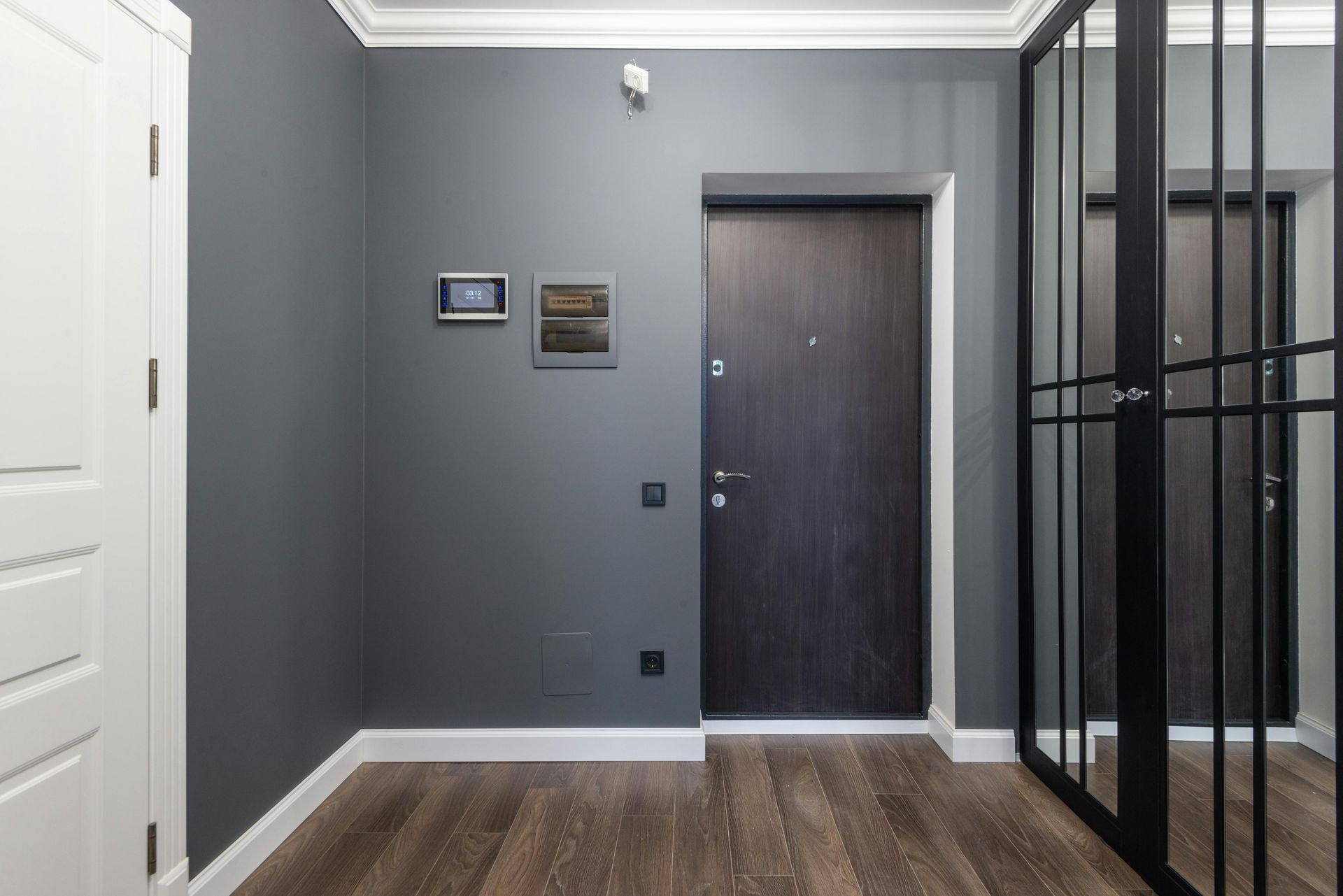 Gray entryway with dark wooden door, mirror, and white trim.