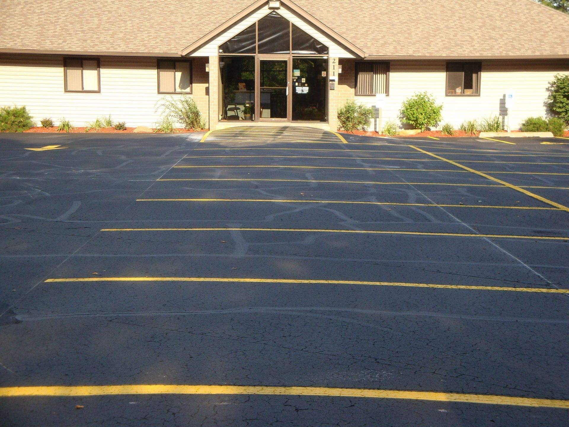 Parking lot in front of a building with a glass door entrance. Yellow parking lines.
