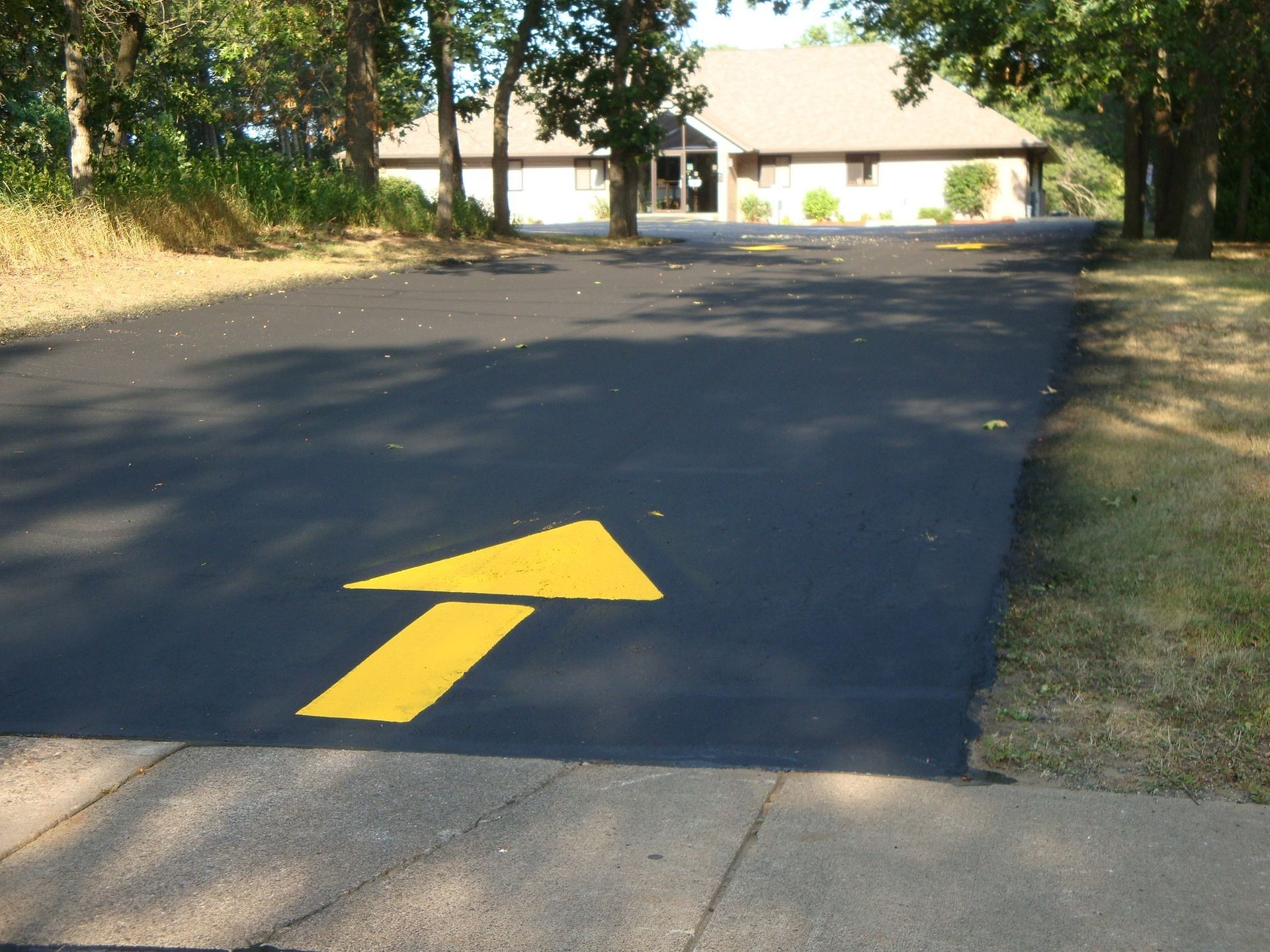 Yellow arrow on asphalt points towards a building.