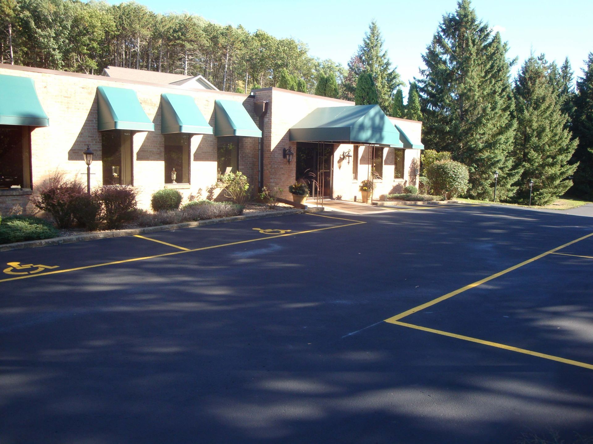 A brick building with green awnings and a parking lot.