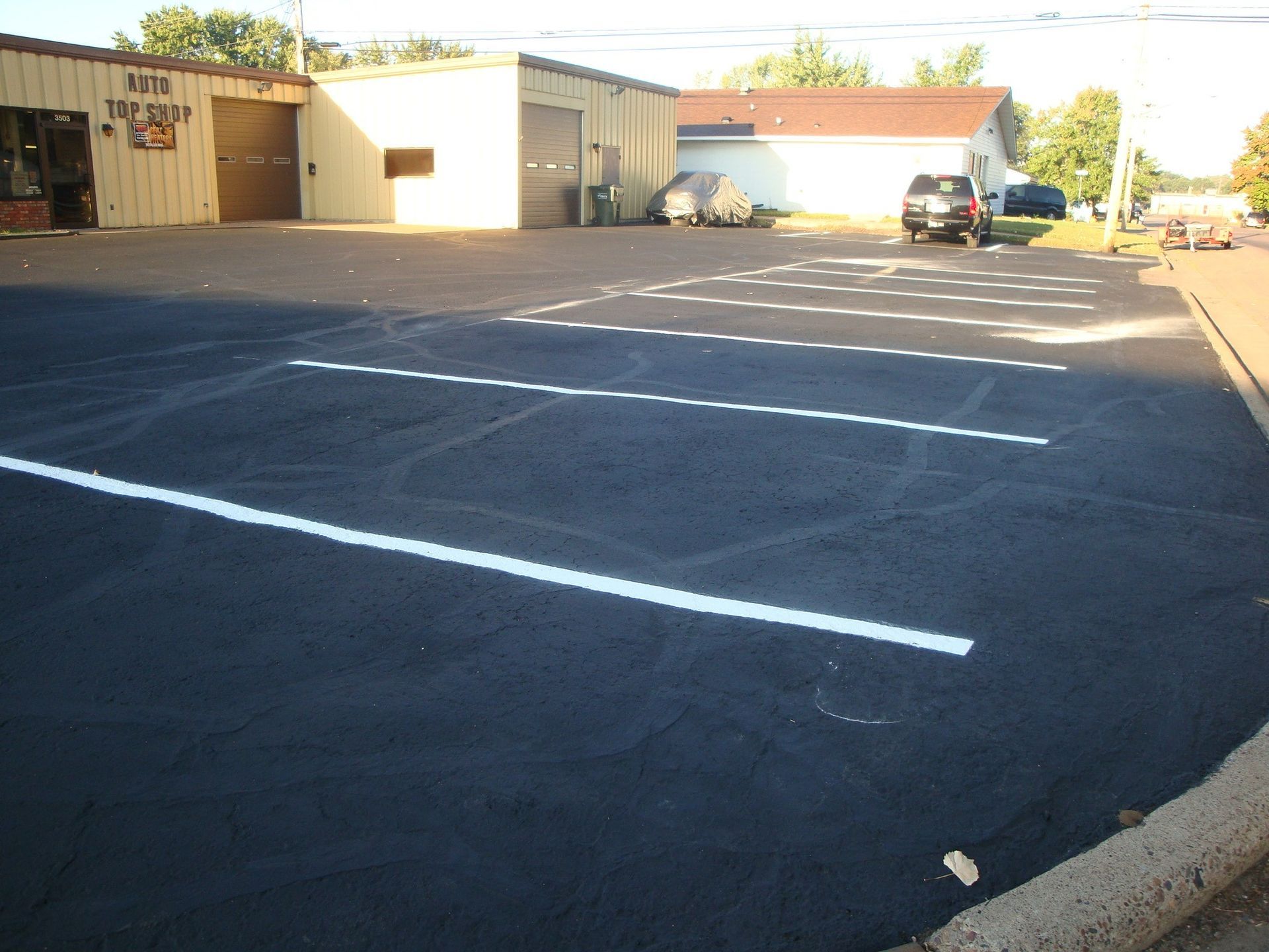 Parking lot with freshly painted white lines in front of a brick building on a sunny day.