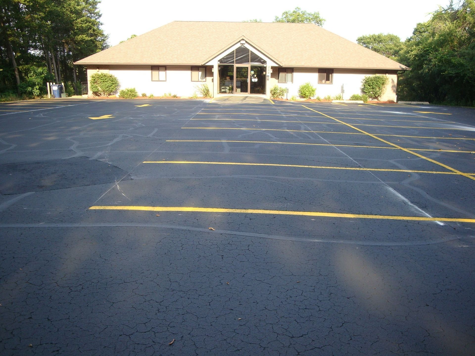 A low-angle view of an asphalt parking lot in front of a one-story building.