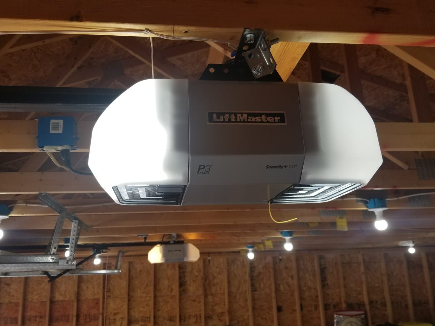 LiftMaster garage door opener in a wooden garage, with multiple lights.