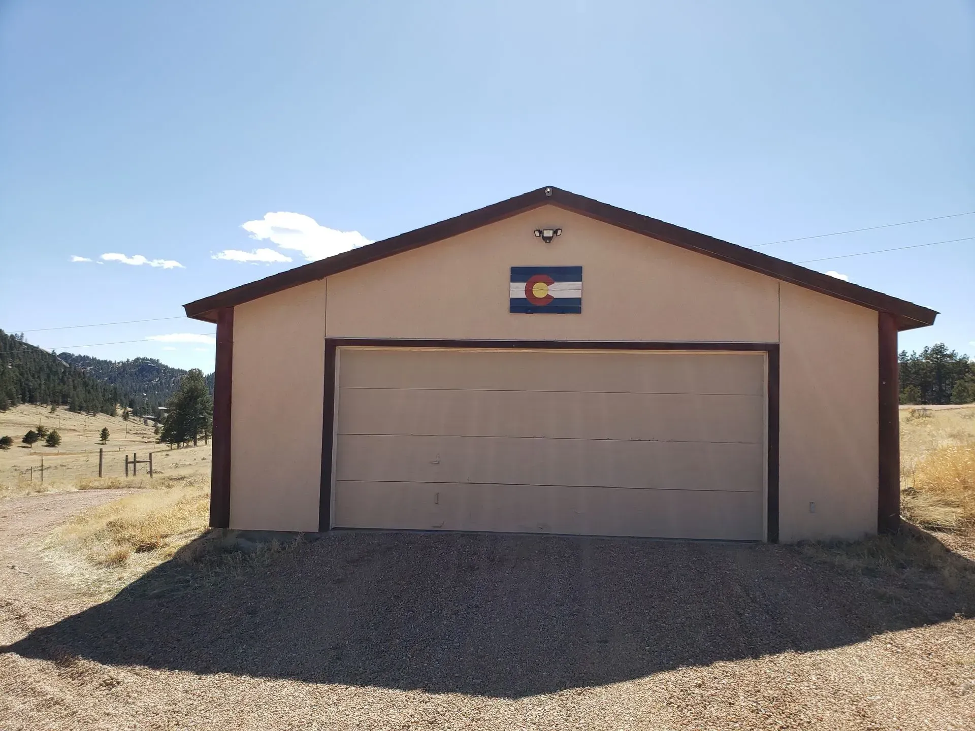 Garage with Colorado flag on a sunny day in a rural setting.