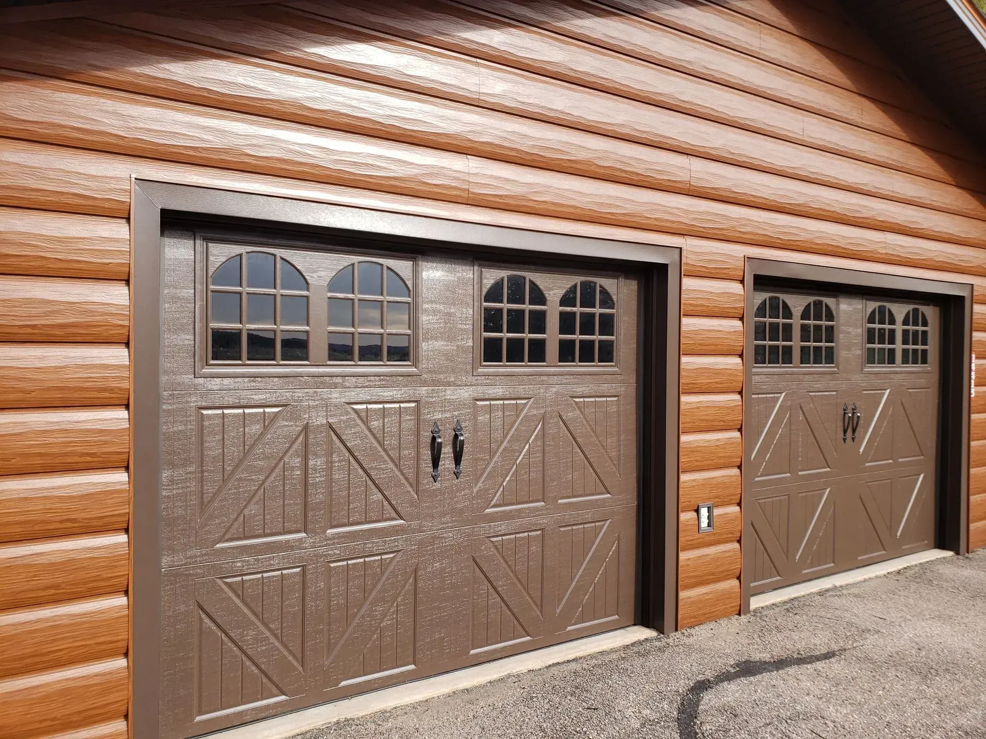 Brown garage doors with arched windows set in a wood-paneled building.