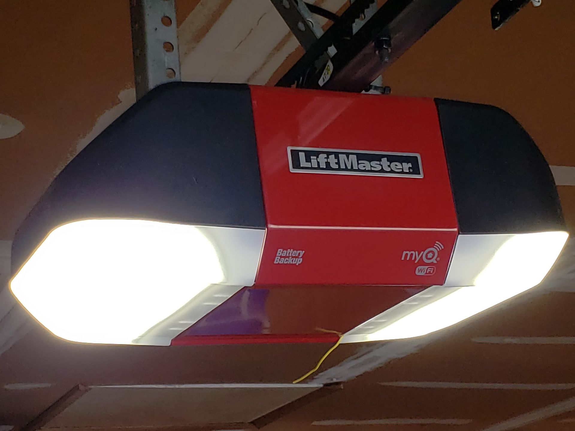 Red and black LiftMaster garage door opener with bright lights.