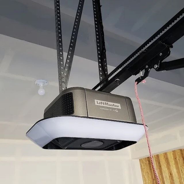 A LiftMaster garage door opener installed on a garage ceiling, with a hanging light.