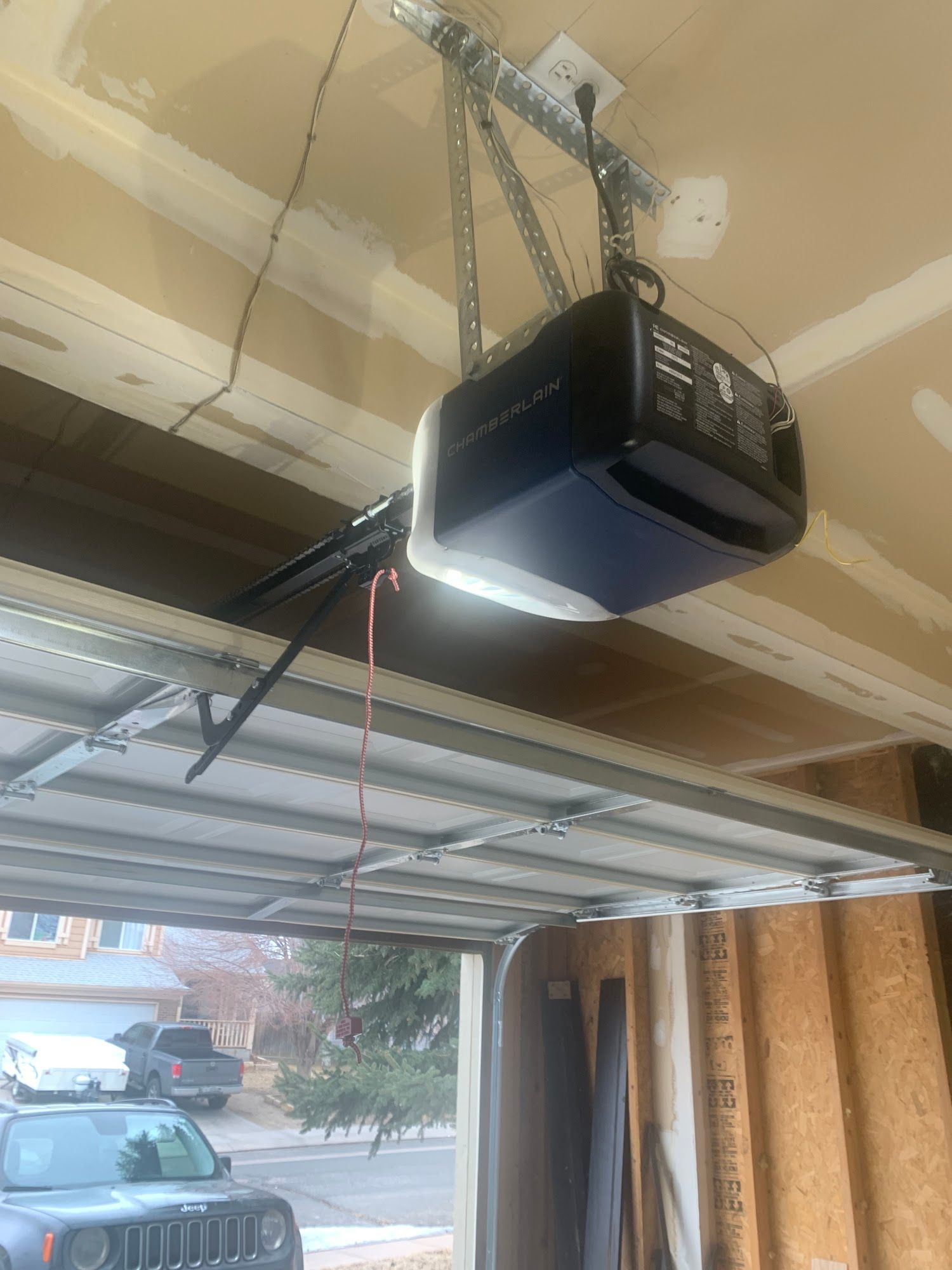 Garage door opener mounted on the ceiling, with the door partially open.