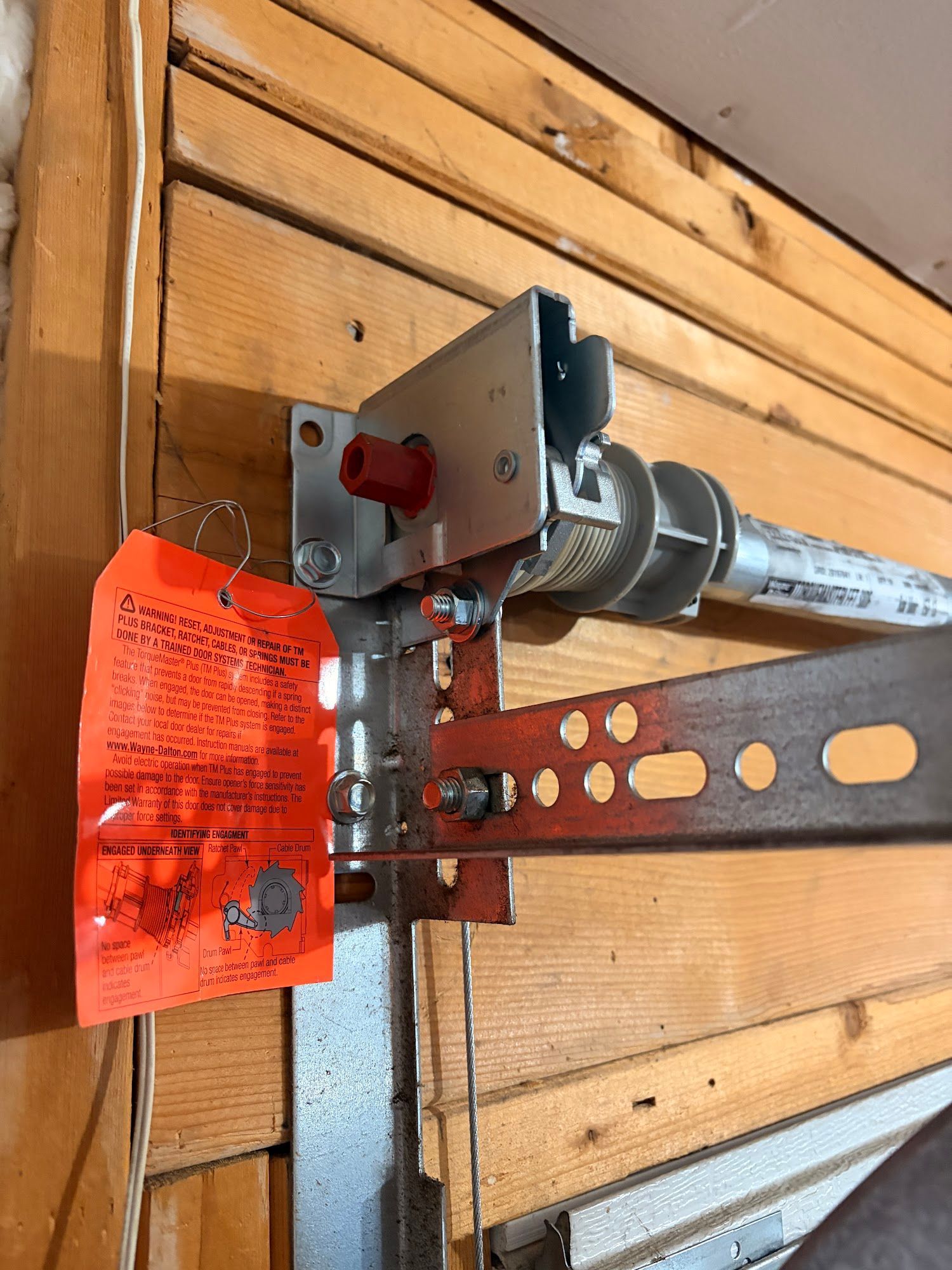 Garage door opener bracket attached to a wooden wall; an orange tag is visible.