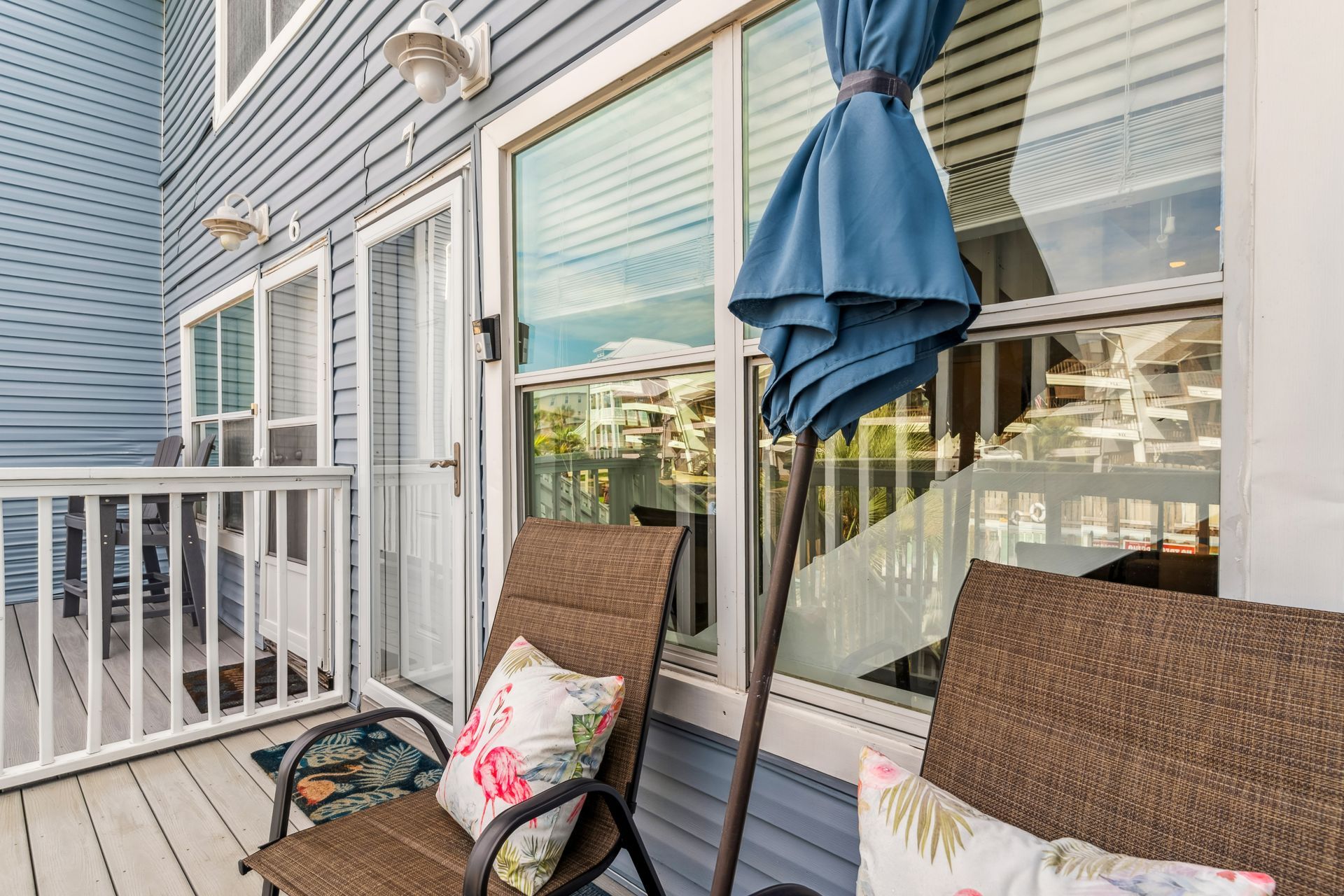 A deck with a chair and umbrella in front of a window.