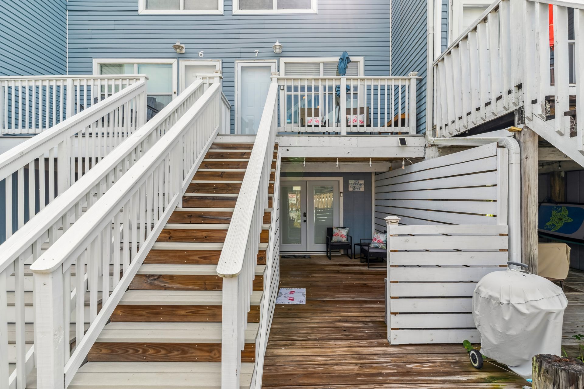 A wooden deck with stairs leading up to it and a white railing.