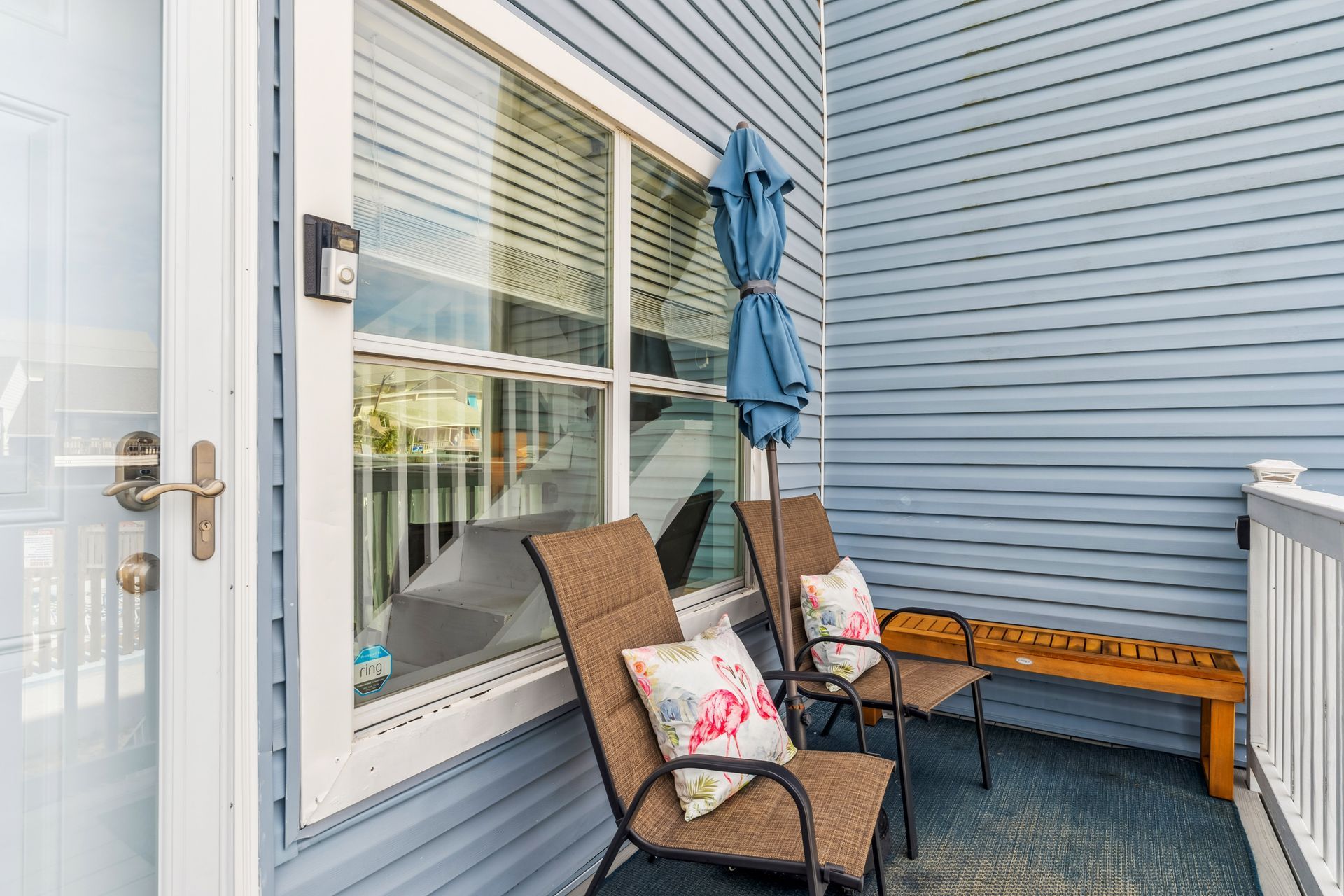 There are two chairs and an umbrella on the porch of a house.