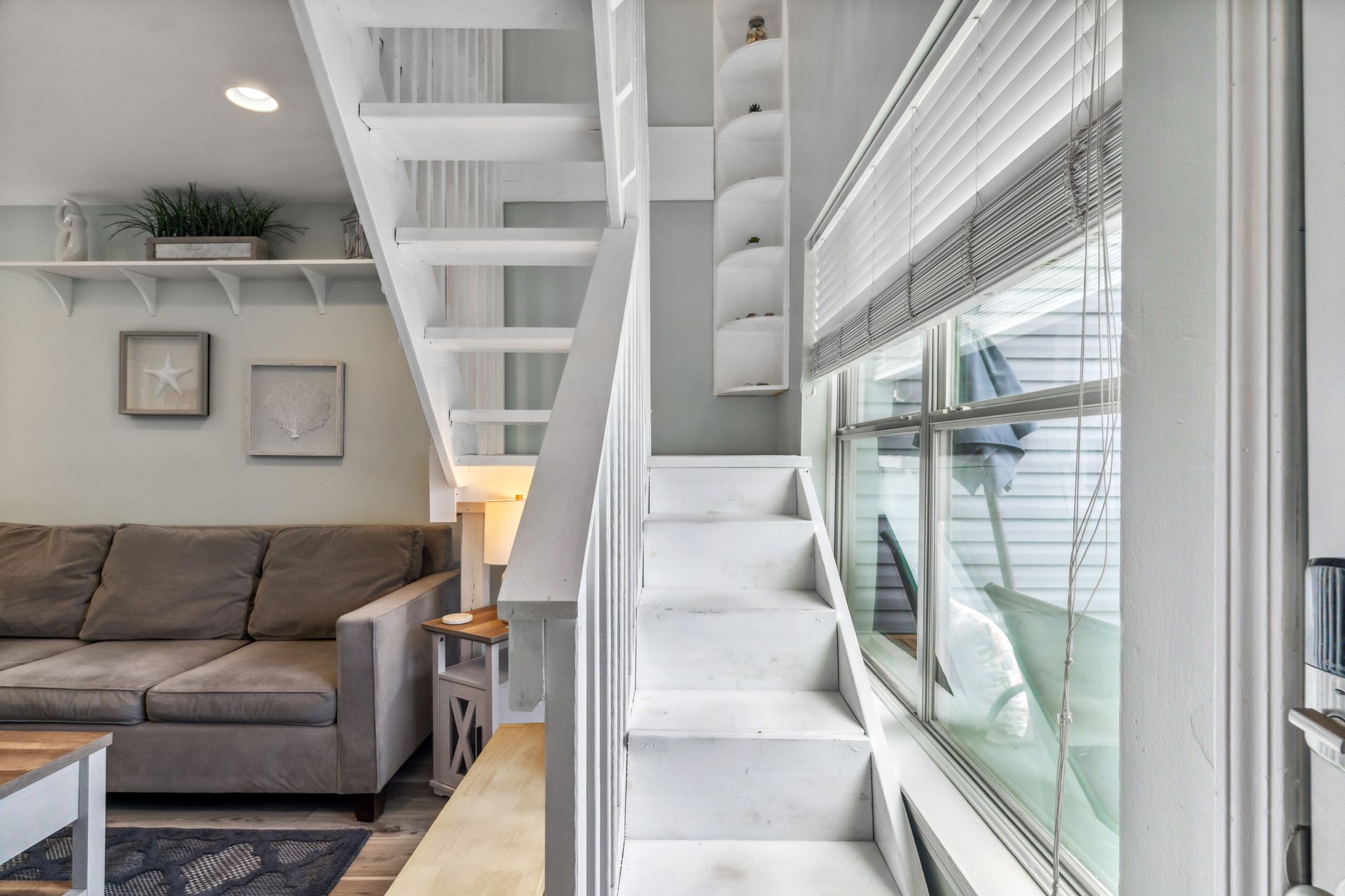 A living room with a couch and stairs leading up to the second floor.