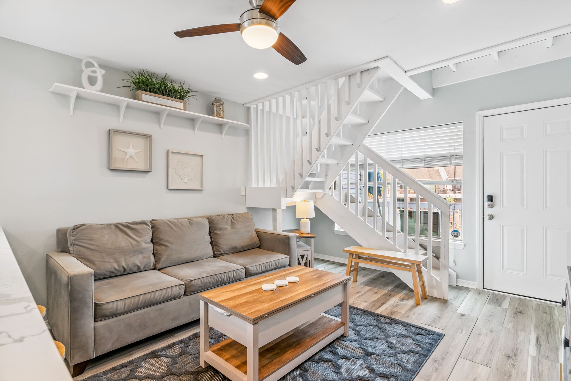 A living room with a couch , coffee table , and ceiling fan.