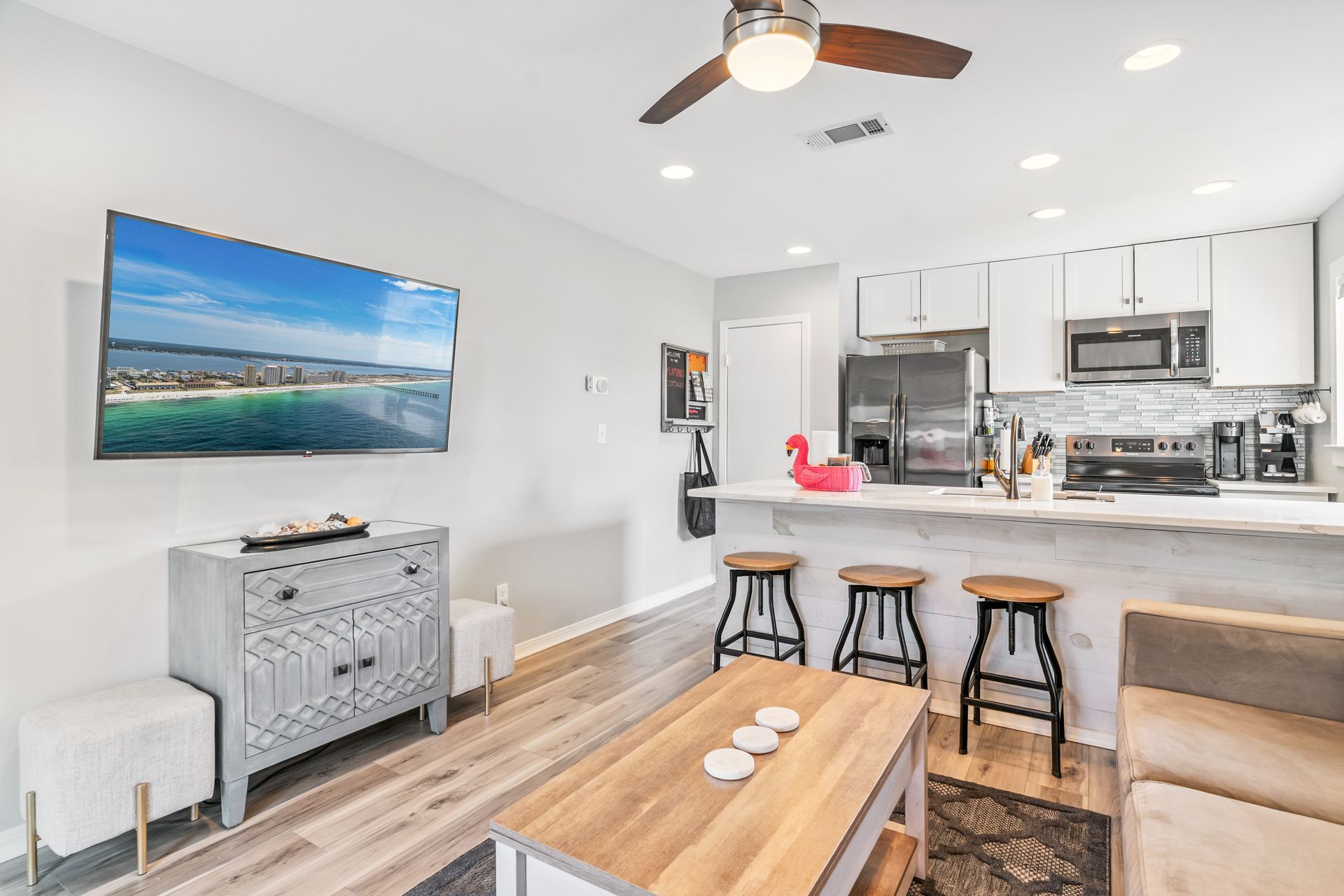A living room with a flat screen tv on the wall and a ceiling fan.