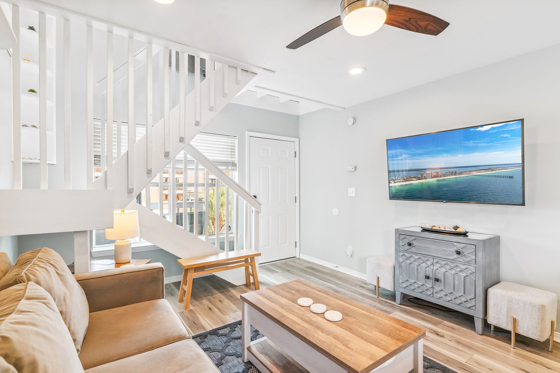 A living room with a couch , coffee table , television and stairs.