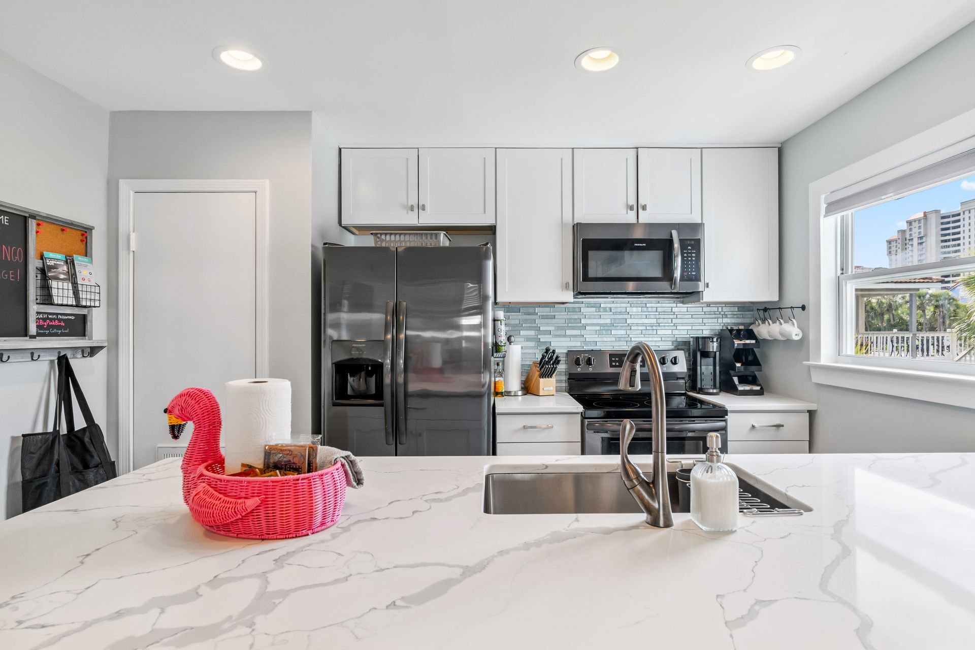A kitchen with white cabinets , stainless steel appliances , a sink , refrigerator and microwave.