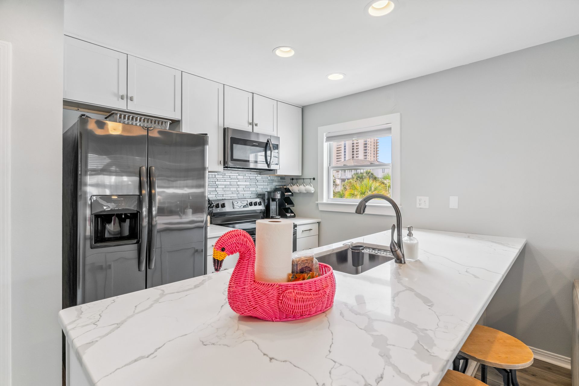 A kitchen with a pink flamingo paper towel holder on the counter.