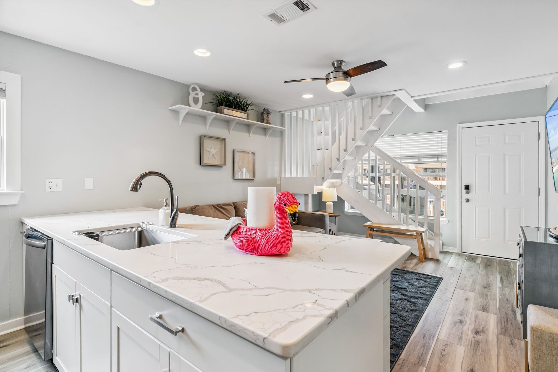 A kitchen with white cabinets , a sink , and a ceiling fan.
