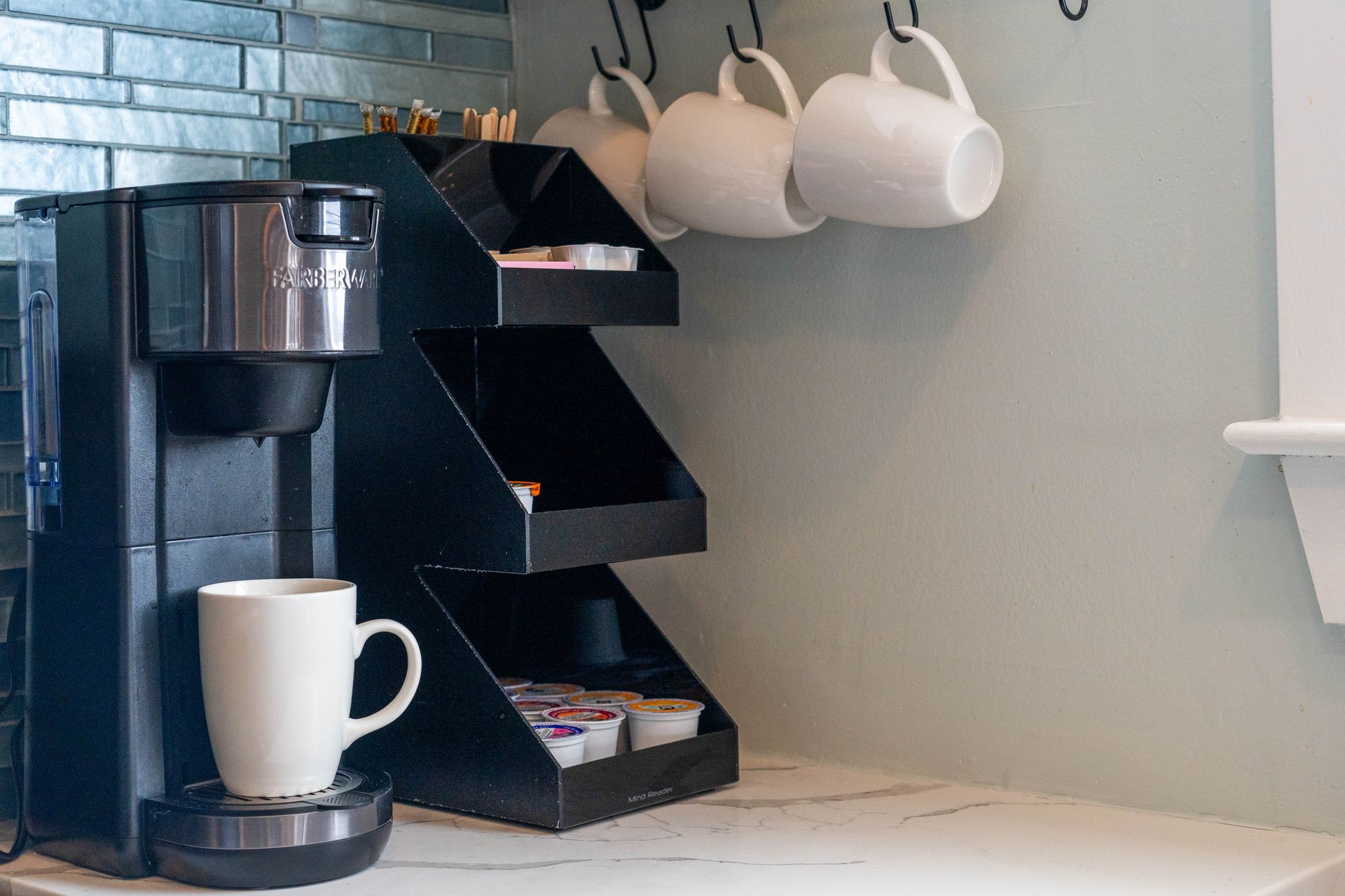 A coffee maker is sitting on a counter next to a cup of coffee.