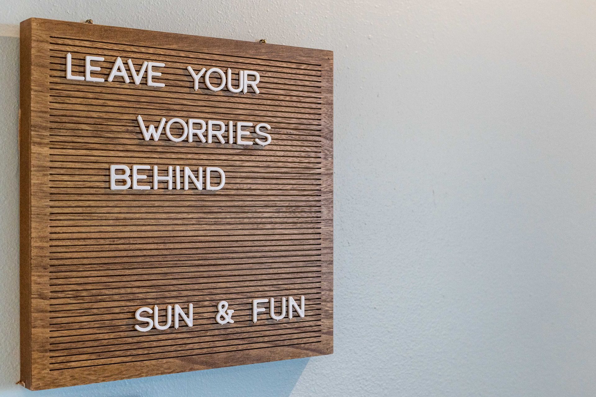 A wooden sign that says leave your worries behind sun and fun