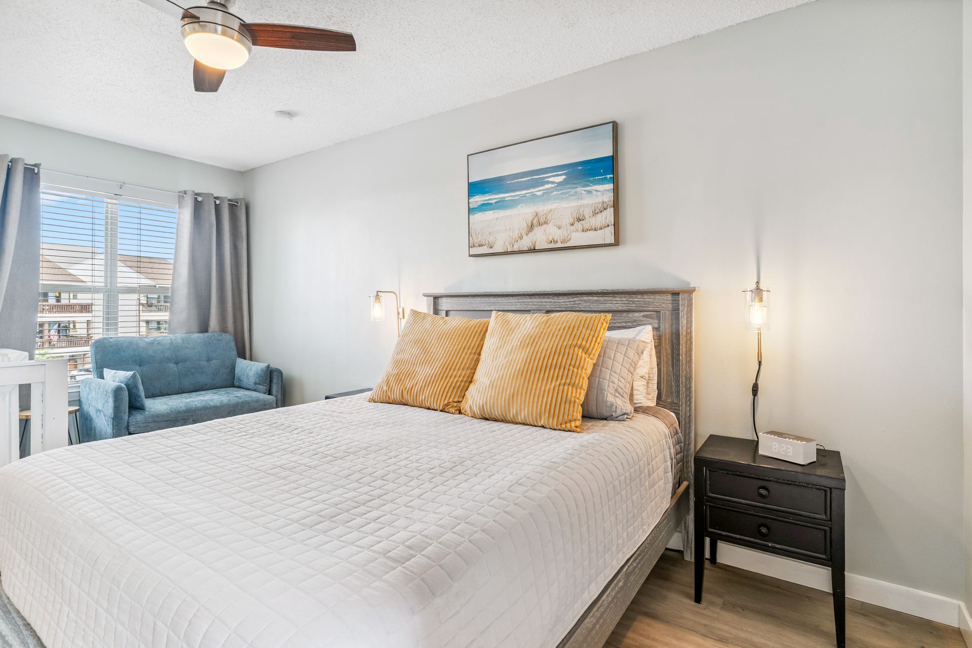 A bedroom with a king size bed , nightstand , chair and ceiling fan.